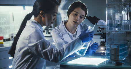Wall Mural - multi ethnic female scientists working late in labolatory. using microscope