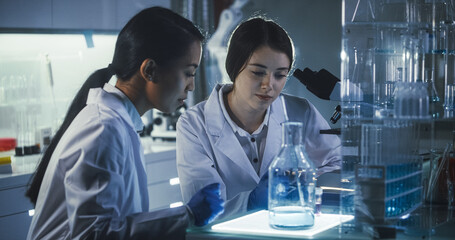 Wall Mural - multi ethnic female scientists working late in labolatory. using microscope