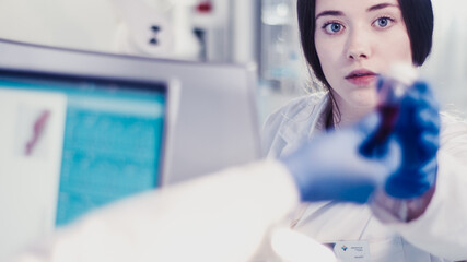Wall Mural - young female doctor working with microscope. close up on face. futuristic laboratory interior