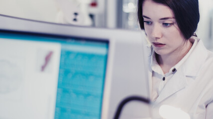 Wall Mural - young female doctor working with microscope. close up on face. futuristic laboratory interior