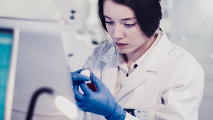 Wall Mural - young female doctor working with microscope. close up on face. futuristic laboratory interior