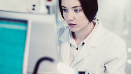 Wall Mural - young female doctor working with microscope. close up on face. futuristic laboratory interior