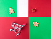 Christmas Geometric Background In Red, Green And White. Gingerbread Cookies, Shopping Cart And Bauble. Colorful Flat Lay. Festive Online Shopping Concept