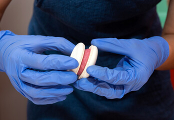 Pastry chef hands in gloves glues macaroon with pink filling.