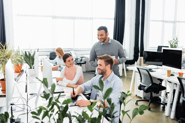 Multiethnic businesspeople using graphics tablet and computers in office