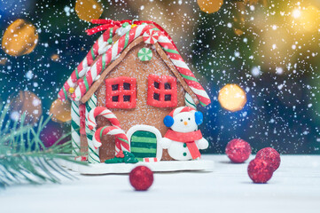 Christmas ginger house with a snowman on the background of blurred colored lights and falling snow