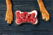 © zontica - Natural raw dog food and dog's paws on black wooden background. Bowl of fresh beef. Healthy eating pet concept.