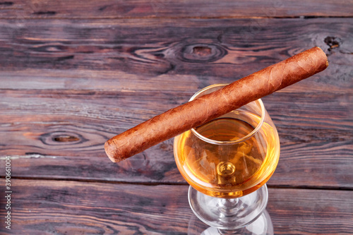 Cuba cigar and glass of brandy top view. Old rustic wooden background.