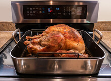 Thanksgiving Or Christmas Turkey In An Oven Roasting Pan. Cooked Holiday Turkey On Stove Top Oven.