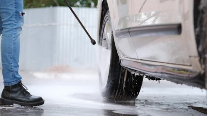 Wall Mural - Woman washing car with high pressure water sprayer during self car washing