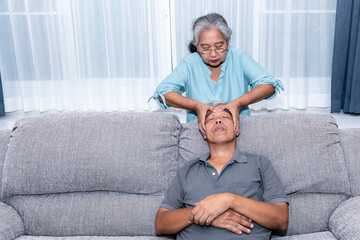 An elderly Asian couple, attractive wife doing reflexology on husband' s face To relax and reduce the pressure, to family and health care concept.