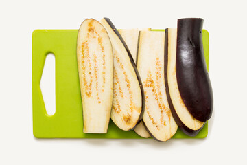 eggplant sliced ​​lengthwise lie on a green board on a white table