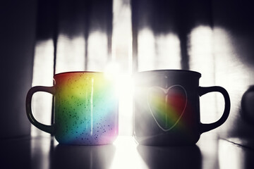 Photo collage. 2 mugs stand next to each other. Rainbow reflex. Concept
