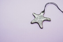 Top View Of Starfish Pendant Isolated On A Purple Background