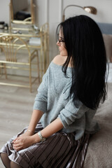 Wall Mural - Young woman with dark hair and in round glasses posing at the dressing table in luxury interior