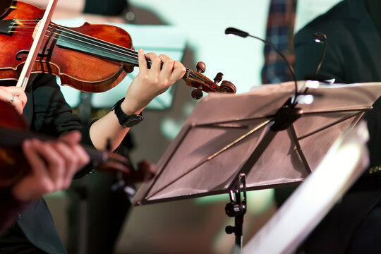Wall Mural -  - Symphony music. Woman playing the violin in orchestra near music note stand
