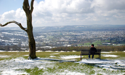 Man sitting on a bench alone in a winter scenery