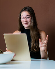 Wall Mural - Vertical shot of a young European woman video chatting using a tablet at home