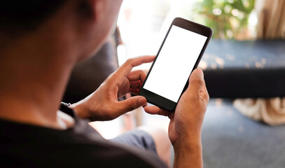 Wall Mural - Cropped shot of young man relaxing on comfortable couch while holding smartphone with blank screen in hands.