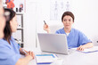© DC Studio - Medical nurse using laptop during briefing with medicine experts in hospital conference room. Clinic therapist with colleagues talking about disease, expert,specialist, communication.