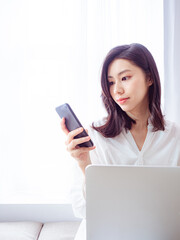 Wall Mural - Young asian woman using smartphone at home