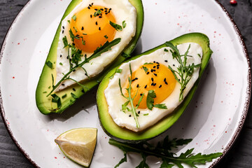 Wall Mural - Fried eggs in avocado with fresh herbs and spices. Avocado stuffed with eggs. Delicious and healthy food. Top view