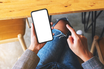 Top view mockup image of a woman holding and pointing finger at mobile phone with blank white desktop screen