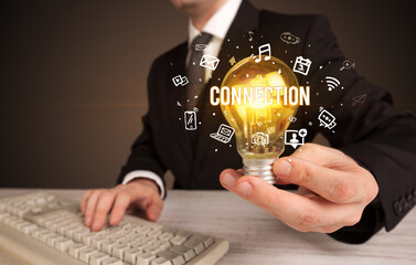 Businessman holding light bulb with CONNECTION inscription, social media concept