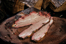 Juicy Piece Of BBQ Beef Brisket Cut Into Pieces On A Wooden Stump Background.