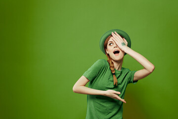 Happy woman with shamrock on St. Patrick's Day in green clothes and a hat on her head gesturing with her hands