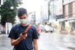 © ijeab - Young man with protective face mask using mobile phone in city street.