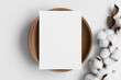 White invitation card mockup on a wooden plate with a dried cotton branch. 5x7 ratio, similar to A6, A5.