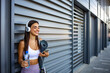 © Dragana Gordic - Young sportswoman texting on the street. A cheerful young woman putting her earphones in before a running session. Young sportswoman outdoors at urban setting, resting and looking away