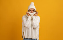 Young Smiling Happy Pretty Blond Woman Wearing White Knitted Sweater, Scarf And Hat, Warm Winter Cold Season Fashion Accessories Trend, Posing On Yellow Studio Background Isolated