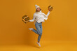 © mary_markevich - young smiling excited pretty woman jumping holding golden present boxes celebrating new year, christmas gifts, wearing white knitted sweater, scarf and hat, winter fashion, on yellow background