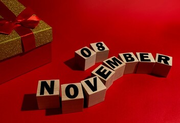 November 8 on wooden cubes ,red gift box on a red background.Autumn .Calendar for November.