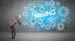 © ra2 studio - Businessman defending with umbrella from MINING inscription, technology concept