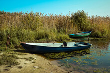 Photo Of A Lake With Boats On The Shore And Reeds
