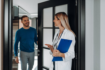 Wall Mural - Doctor welcoming a male patient to her office in modern clinic.