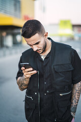 Wall Mural - Young hot tattooed man on his phone checking his new messages