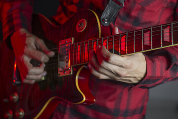 Sticker - Closeup shot of a man's hand playing an electric guitar in a neon light