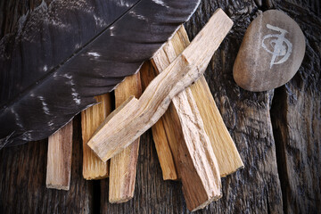 A top view image of a reiki healing symbol and palo santo smudge sticks on a dark wooden table top. 