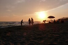 People Walking On The Tuscan Beach At Sunset