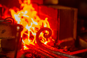 The metal spiral is heated to red in the forge in the forge during forging