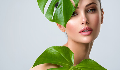 beautiful woman with green leave near face and body. closeup girl's face with green leave. skin care