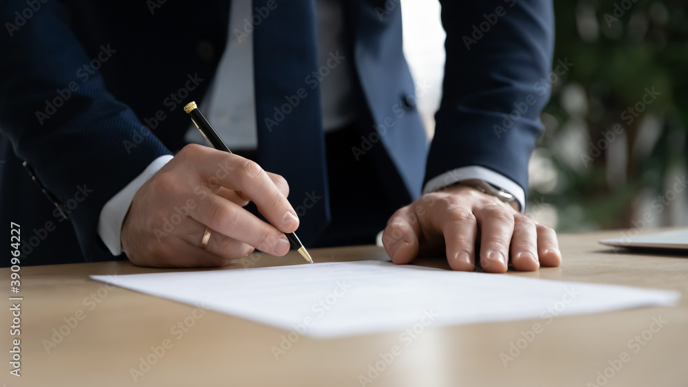 Close up young businessman standing near table with pen in hands, ready signing profitable offer agreement after checking contract terms of conditions, executive manager involved in legal paperwork. - obrazy, fototapety, plakaty 