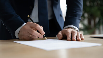 close up young businessman standing near table with pen in hands, ready signing profitable offer agr