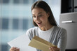 © fizkes - Unbelievable. Excited overjoyed millennial woman corporate worker employee receiving hardcopy of promotion reward notification, happy young female intern getting official letter with hiring decision