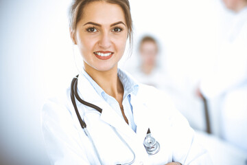 Wall Mural - Female doctor smiling on the background with patient in the bed and two doctors