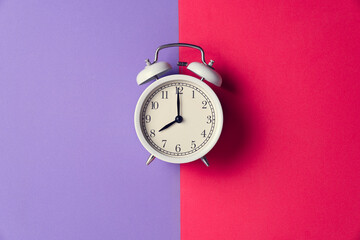 Wall Mural - Retro alarm clock on red and purple table background, vintage lifestyle concept